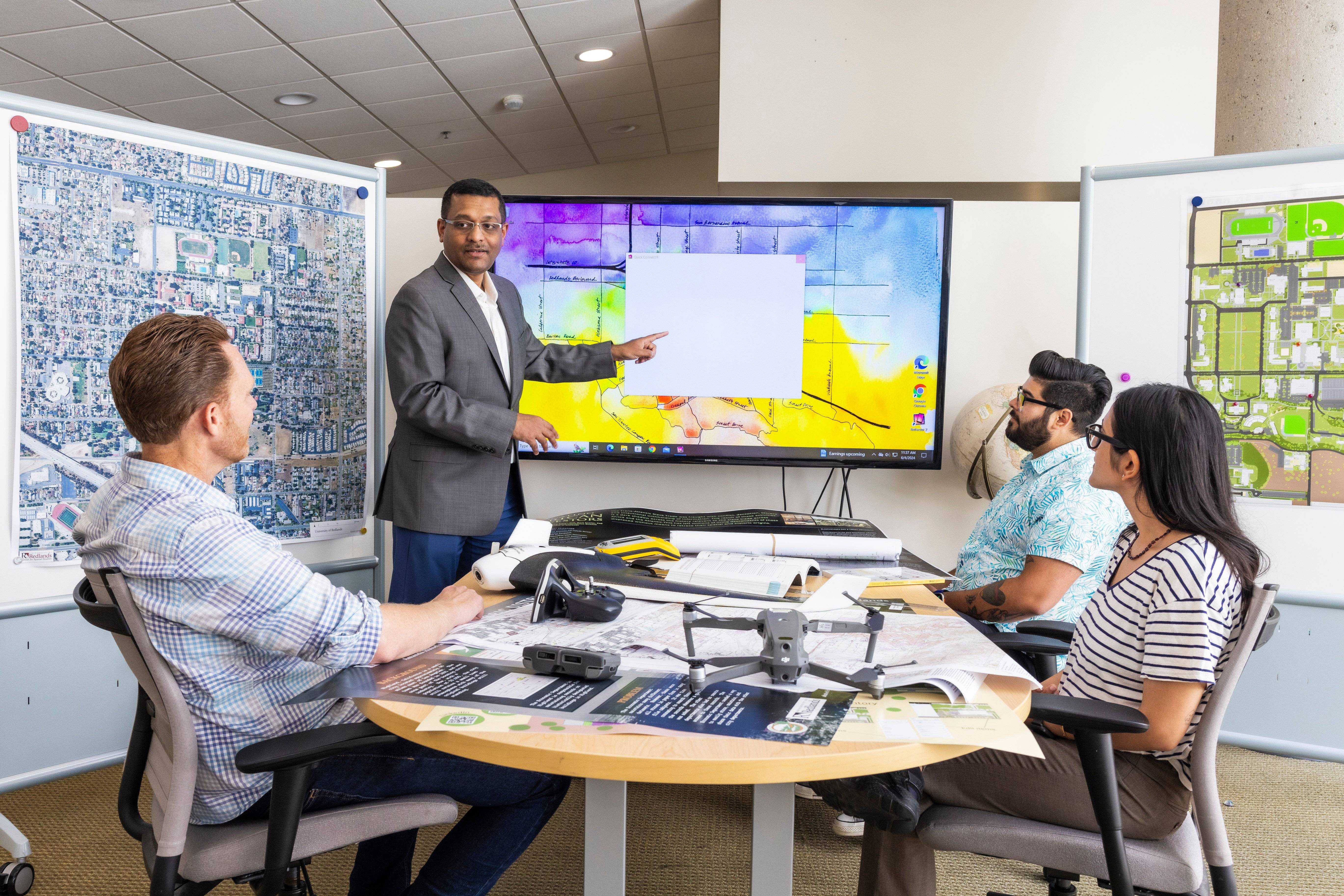 Students sitting around conference table while instructor is pointing at GIS map.