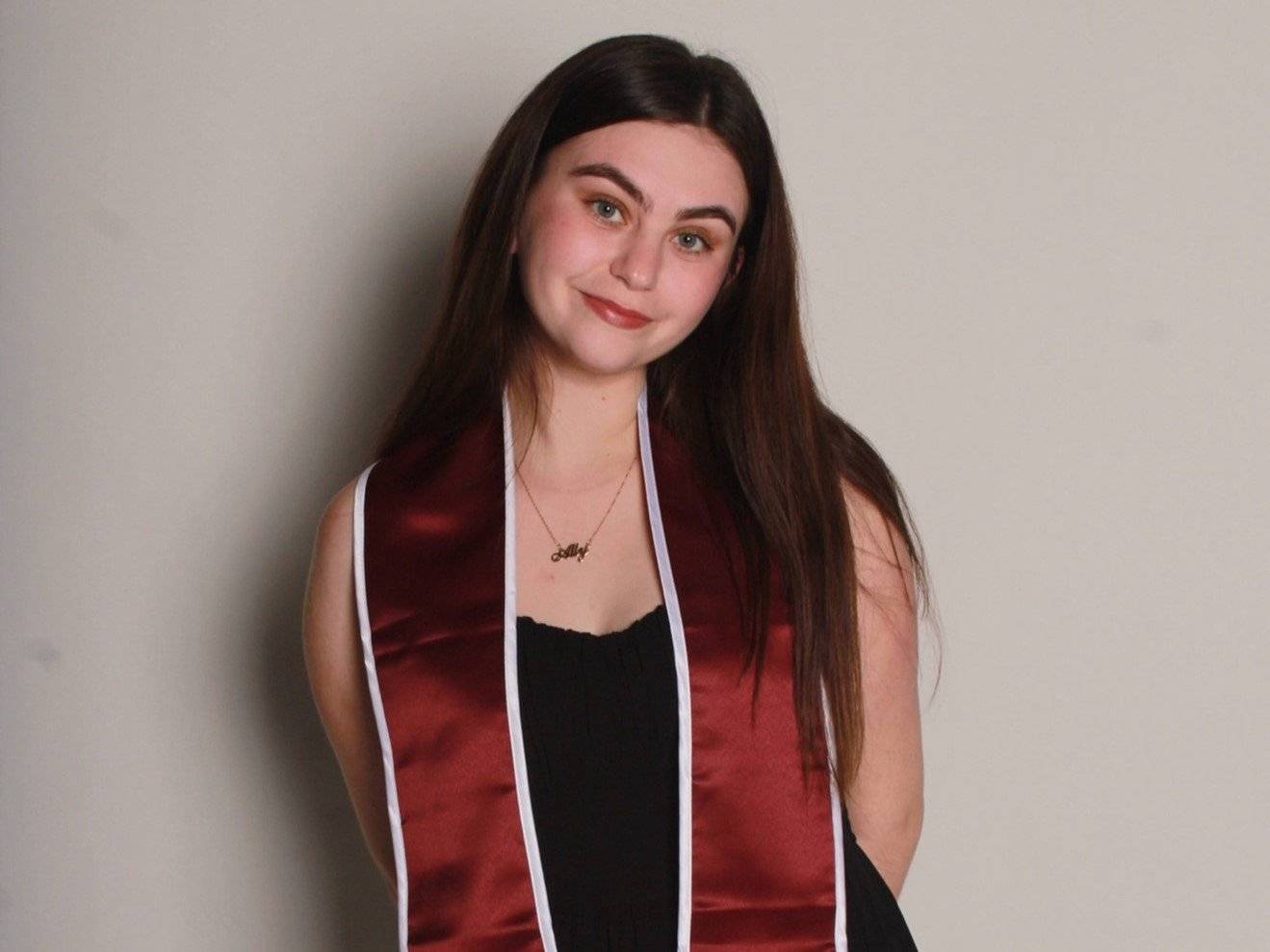a woman wearing a red and black dress and a sash