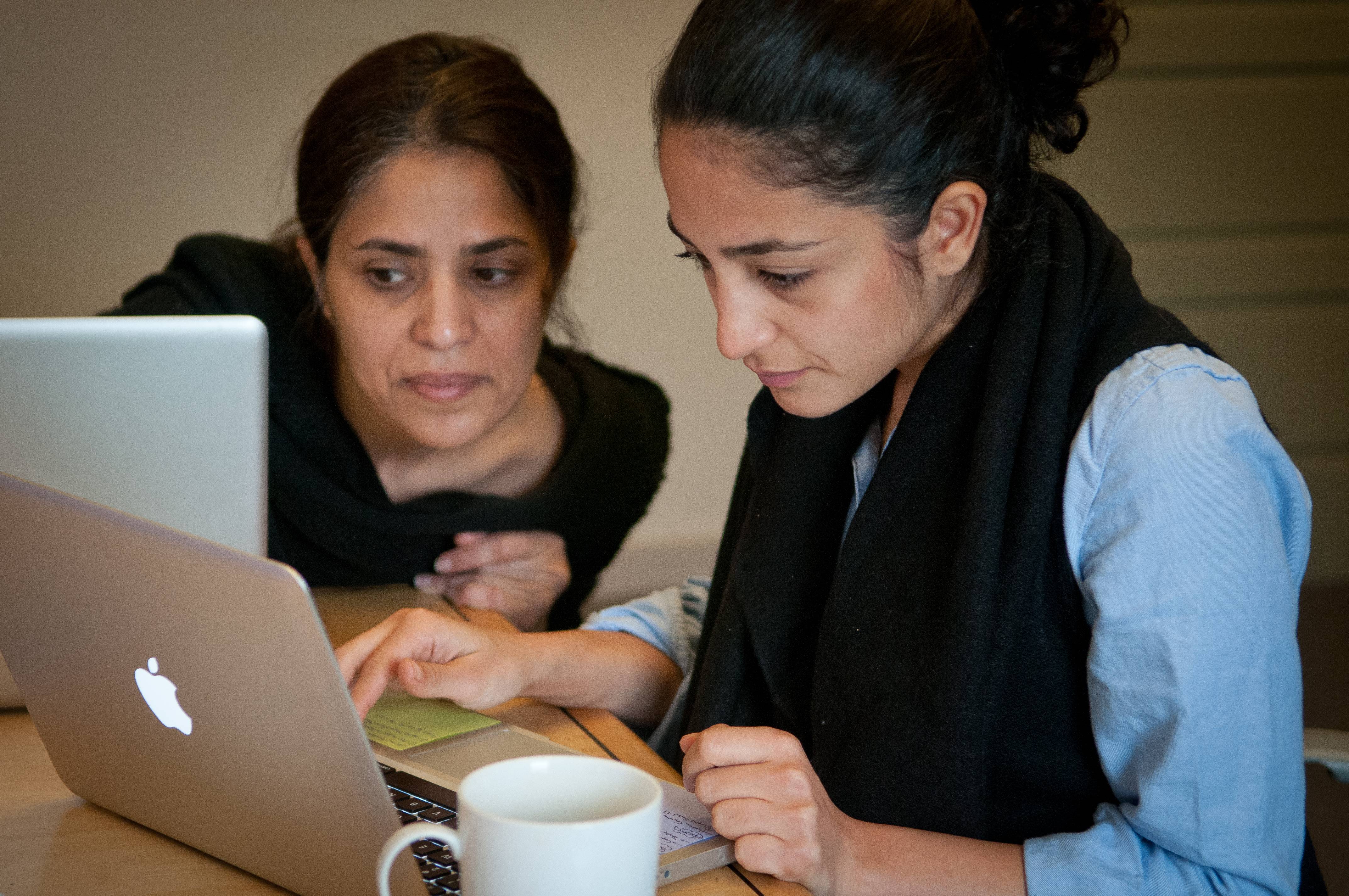a couple of women looking at a laptop