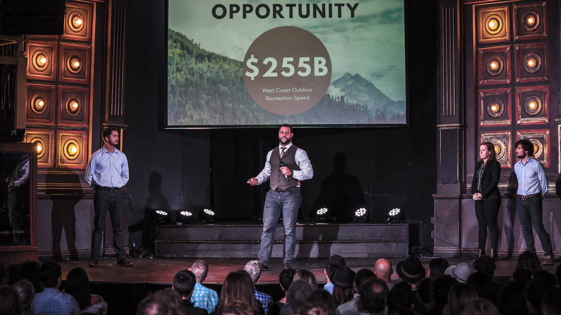 a man on a stage with a large screen and a large crowd