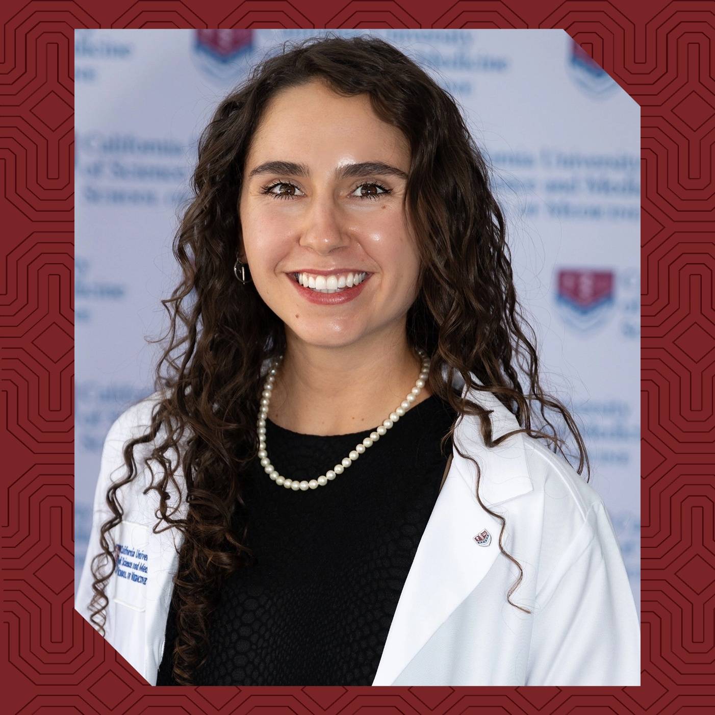 a woman with long curly hair wearing a white lab coat