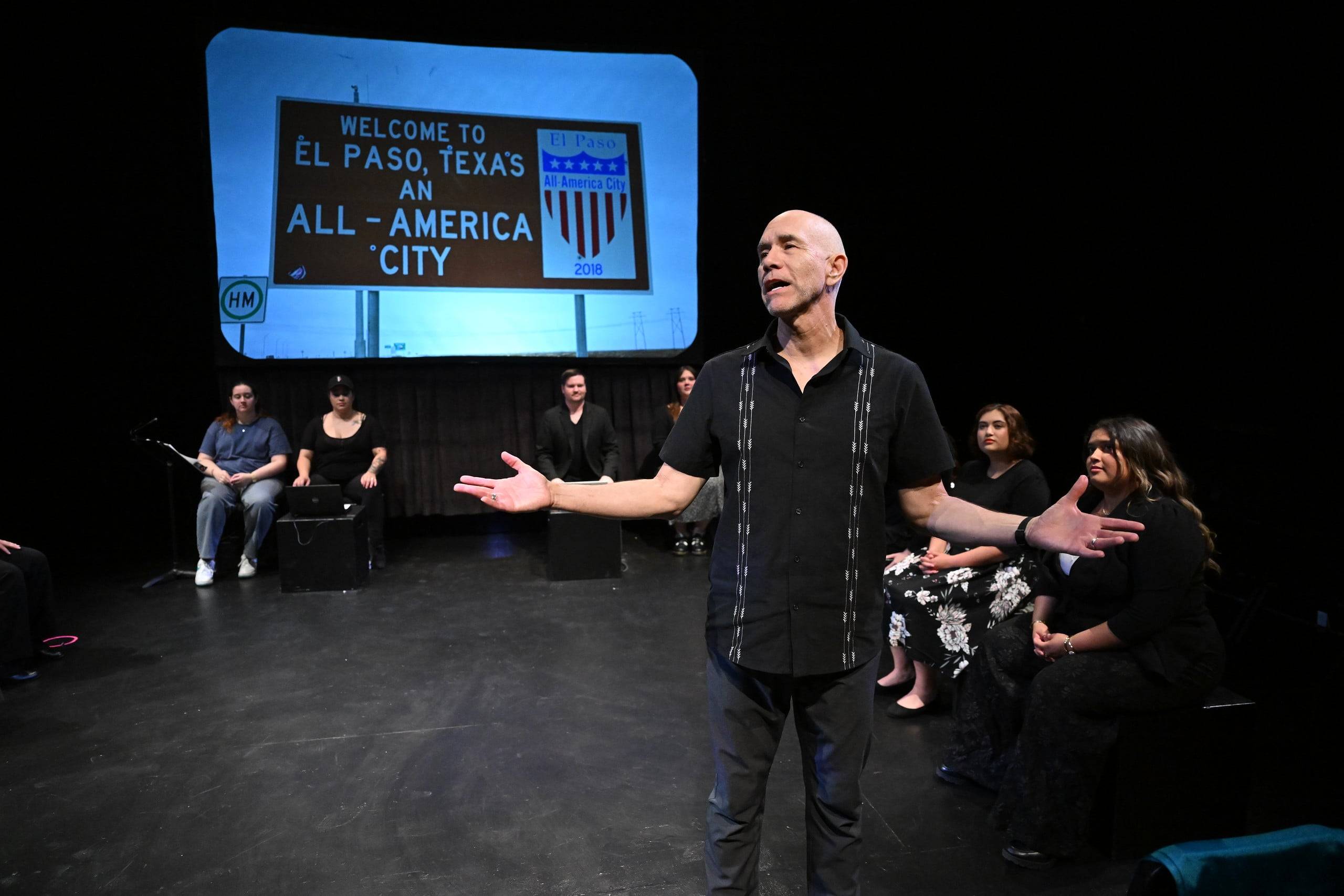a man standing on a stage with his arms out