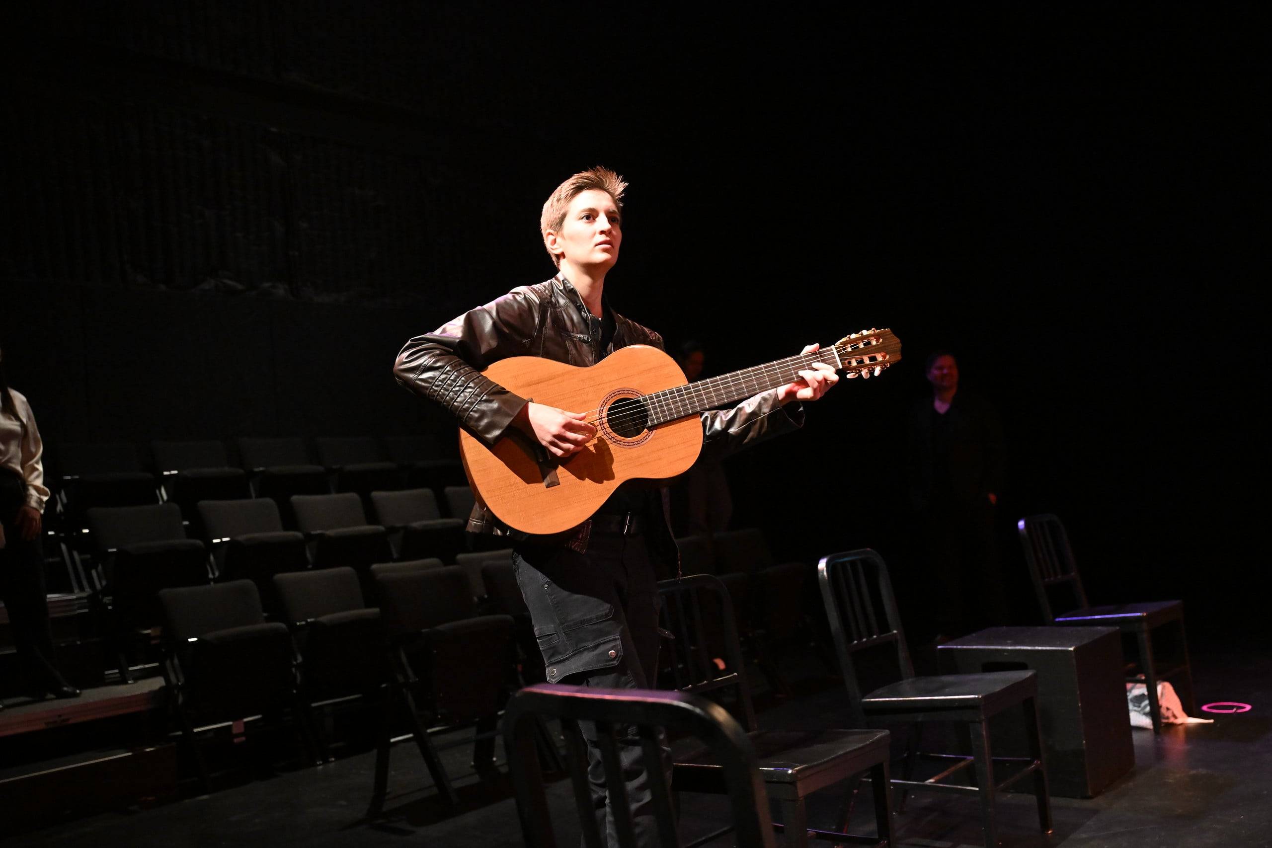 a man playing a guitar in a dark room
