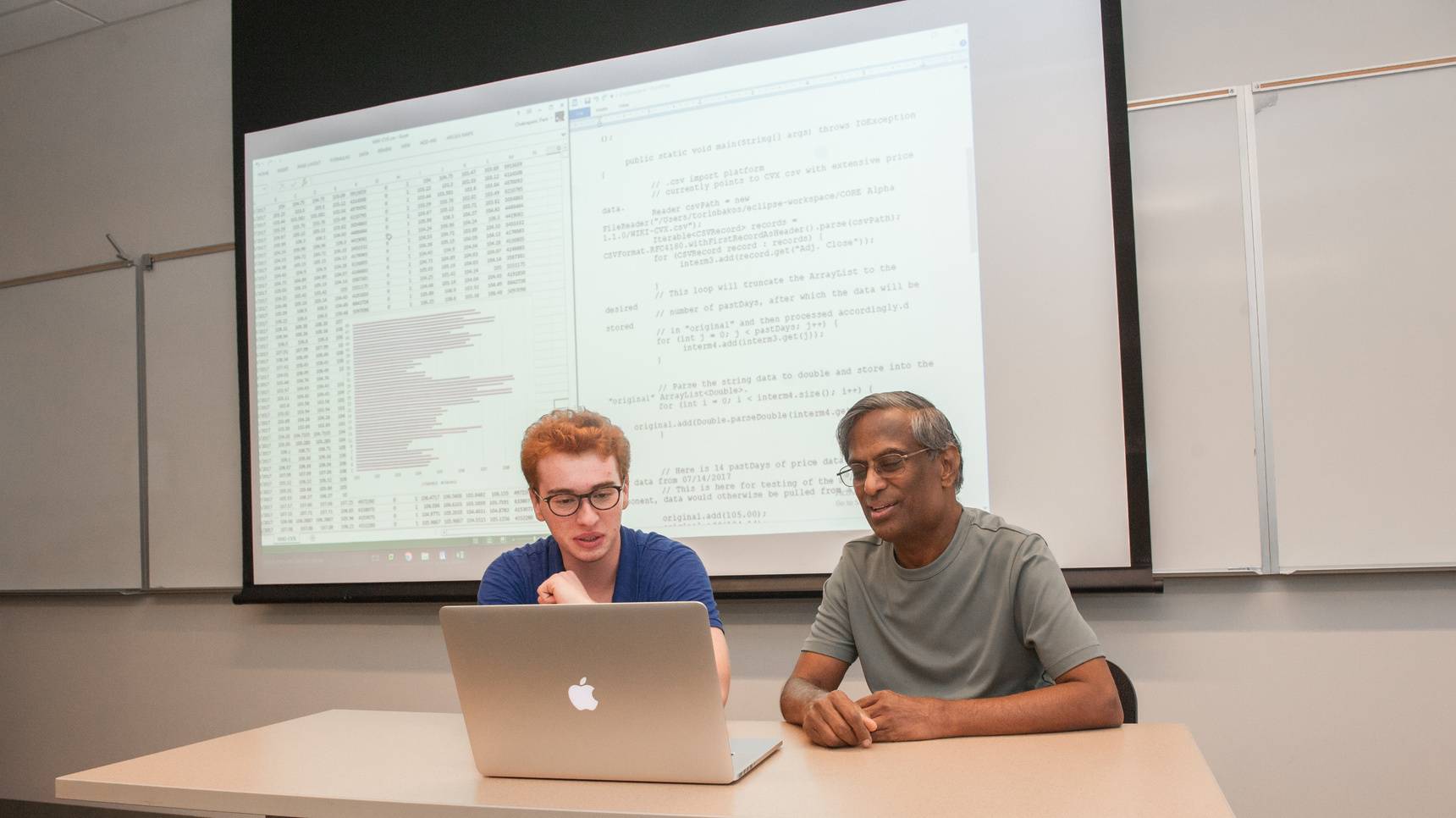 a man and woman sitting at a table looking at a laptop