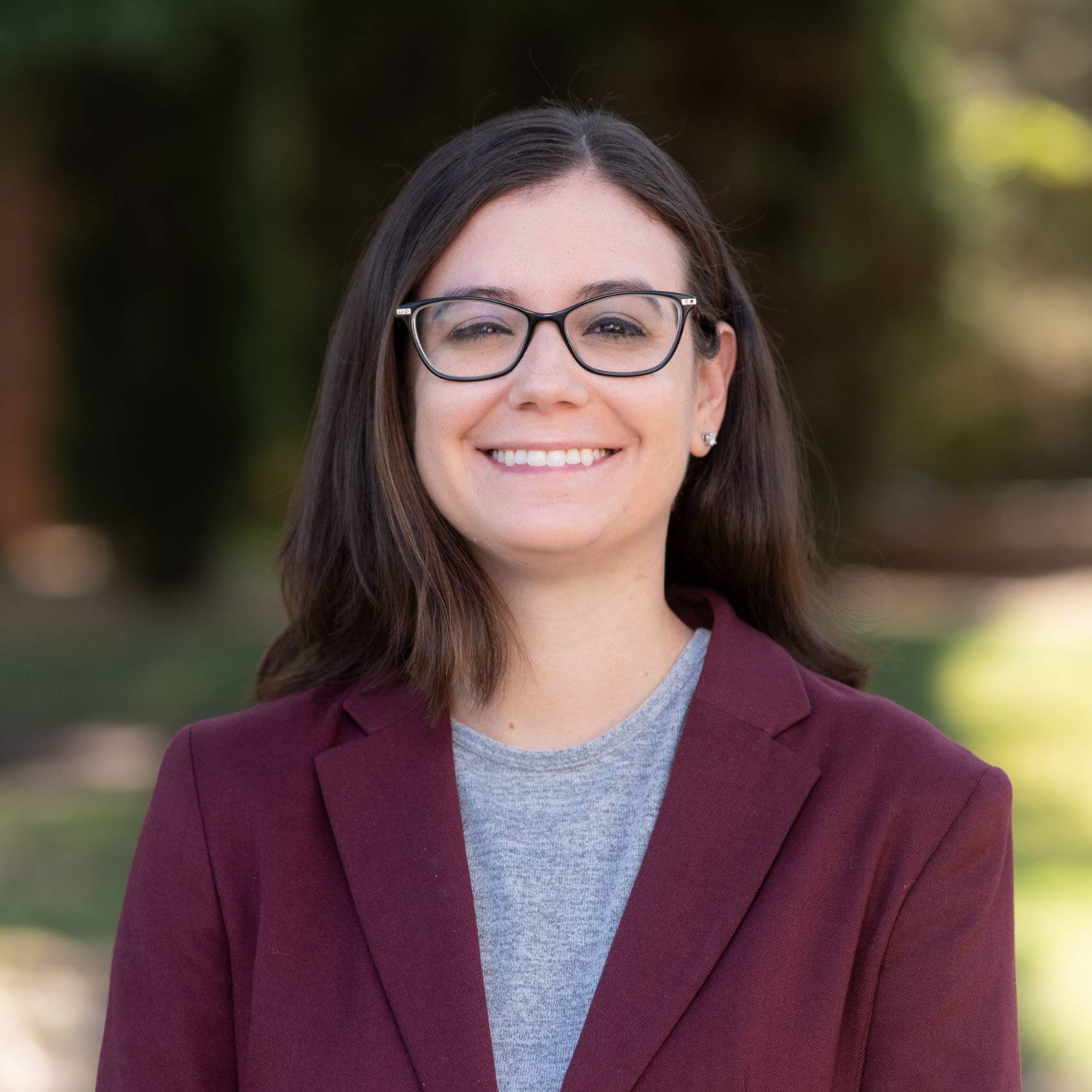 a woman wearing glasses and a red blazer