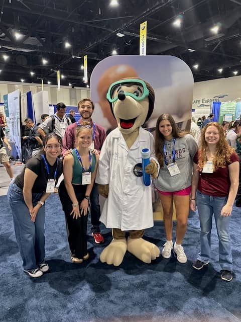 a group of people posing for a photo with a mascot