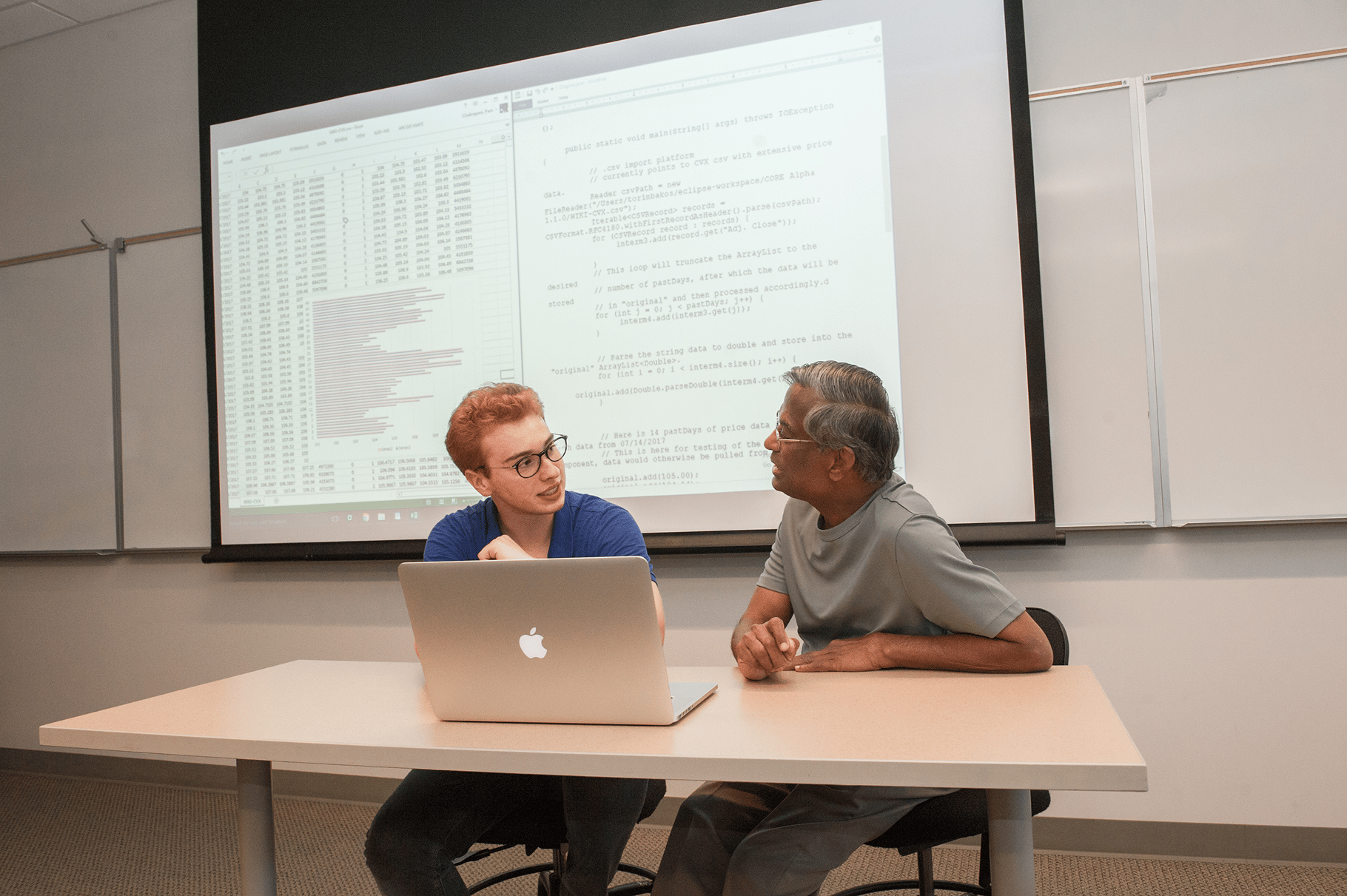 a man and woman sitting at a table with a laptop