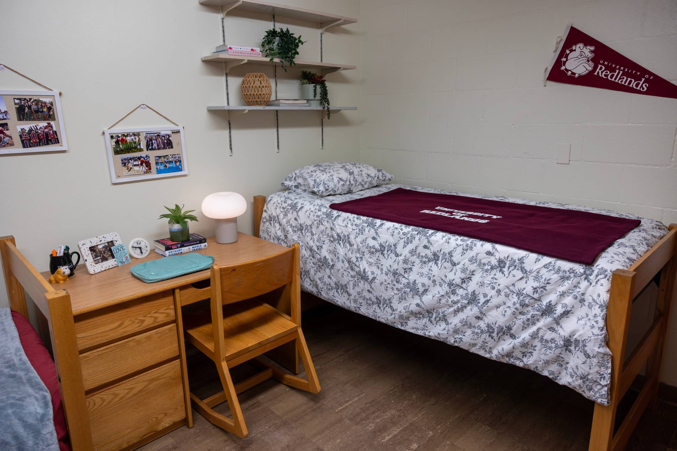 a bed with a red blanket and a desk in a room