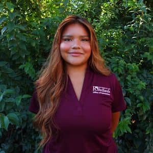 a woman standing in front of bushes