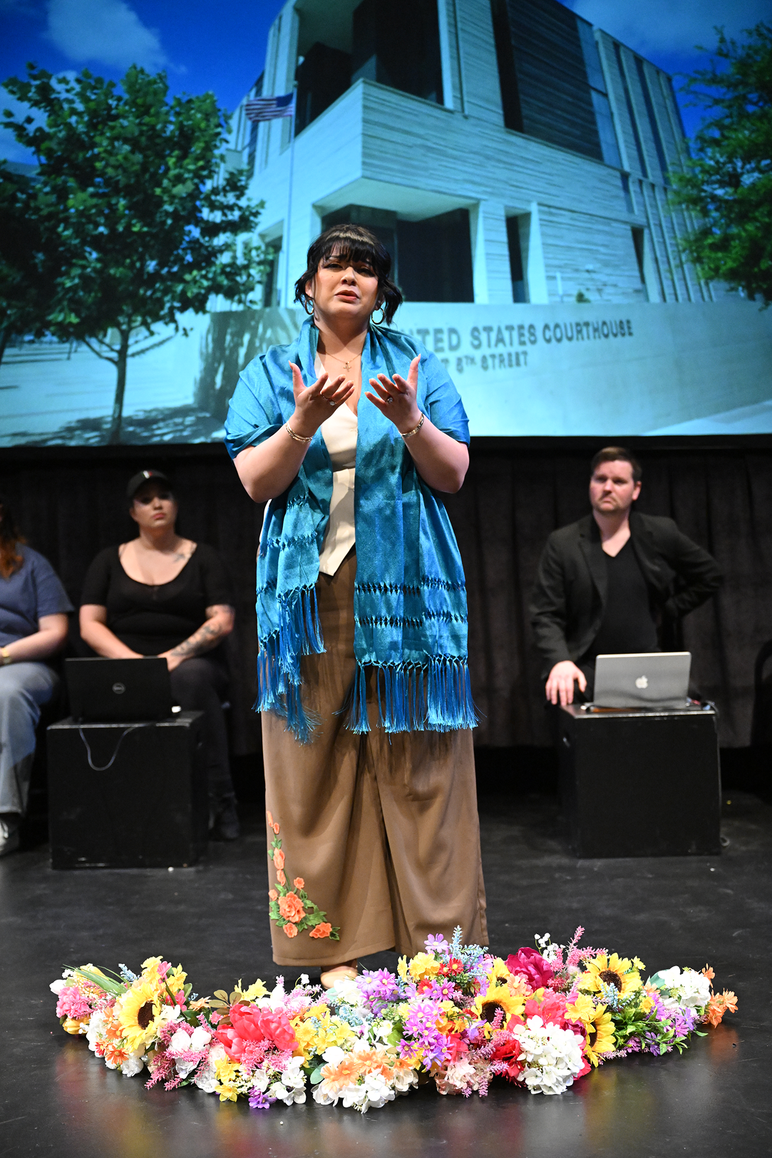 a woman standing on a stage with a group of people behind her
