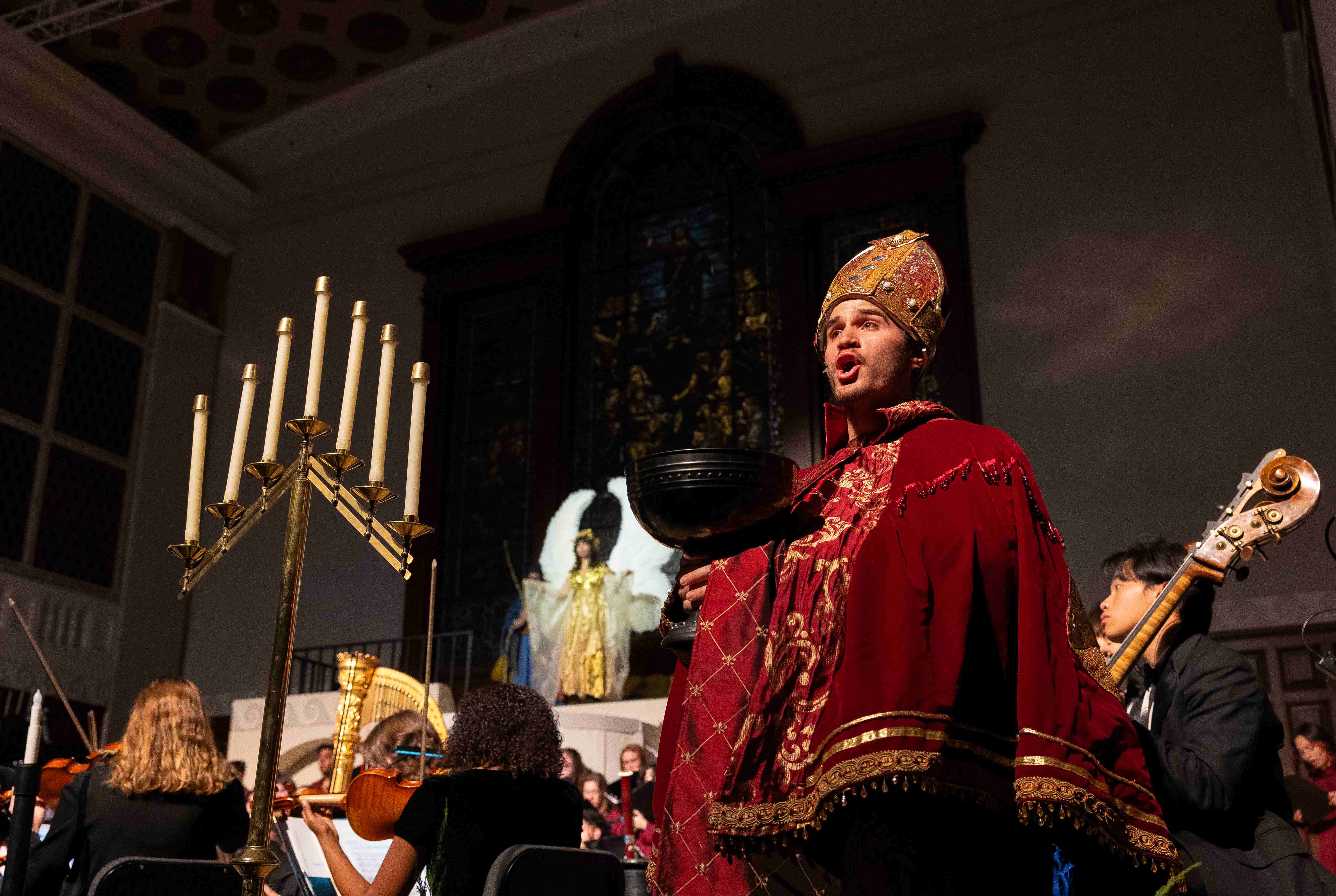 a man in a red robe and gold hat holding a bowl