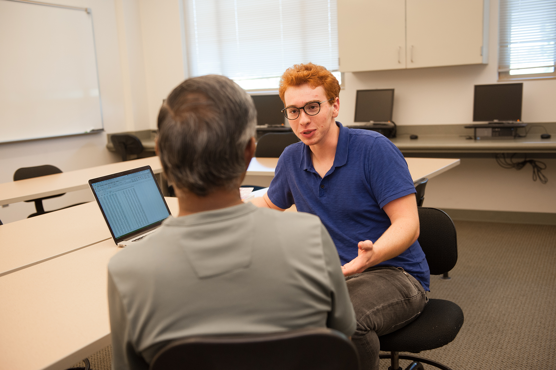 a man sitting in a chair talking to a man