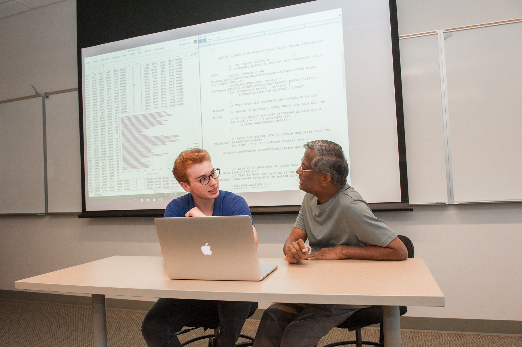 a man and woman sitting at a table with a laptop
